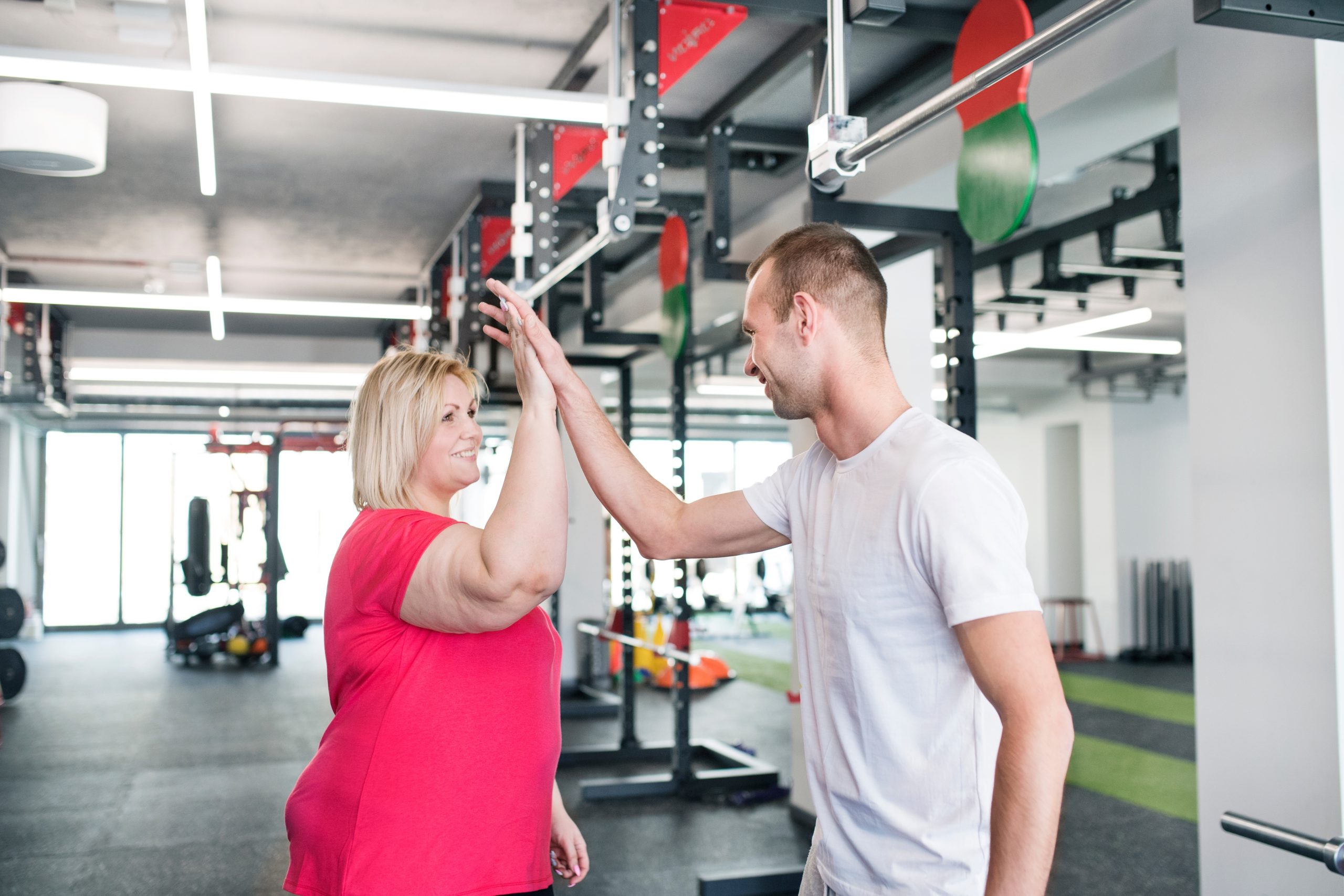 Fitness specialist celebrating achievement with client during weight management program in YMCA Level 4 Certificate in Weight Management