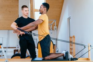 Pilates instructor supervising client performing kneeling exercise on reformer machine in YMCA Level 3 Certificate in Instructing Pilates